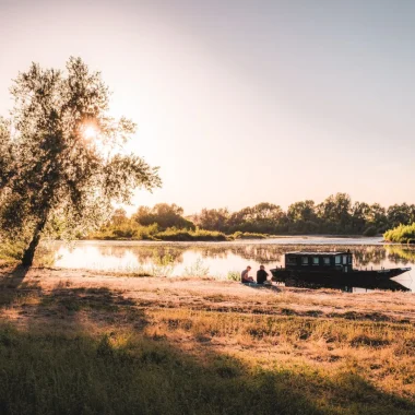 Couple assis sur les bords de Loire, un bateau amarré devant eux