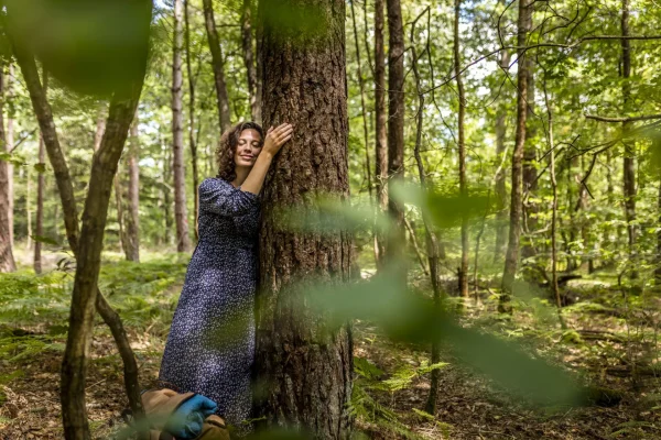 Femme qui fait un calin à un arbre dans la forêt